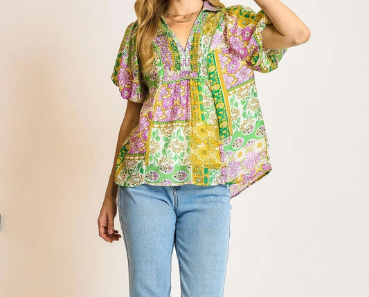 Woman wearing a colorful patterned top and blue jeans on a plain background