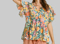 Woman wearing a colorful floral dress against a beige background