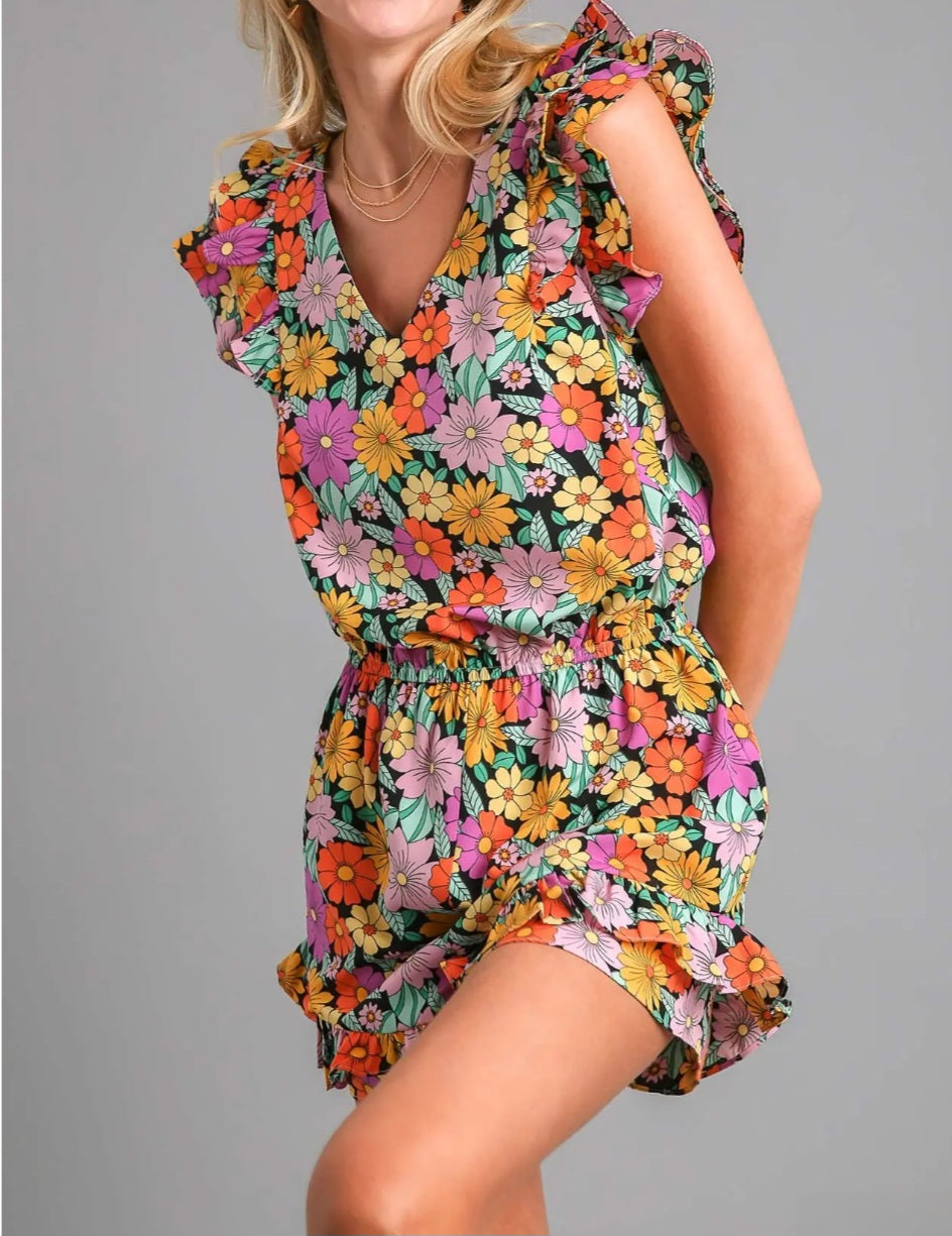 Woman wearing a colorful floral romper on a gray background