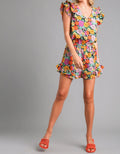Woman wearing a colorful floral romper  on a gray background