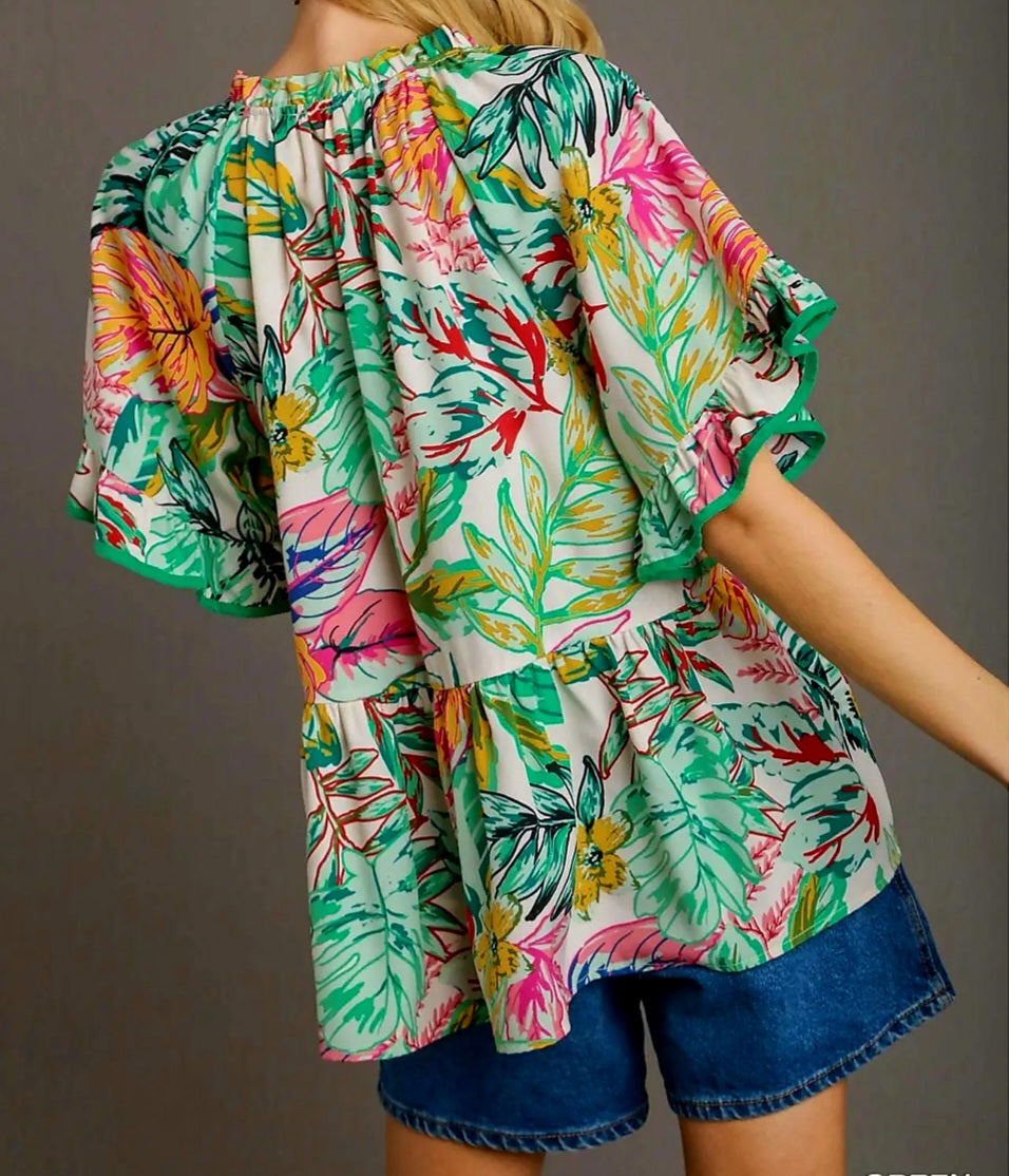 Colorful tropical floral blouse with ruffled sleeves on a plain background