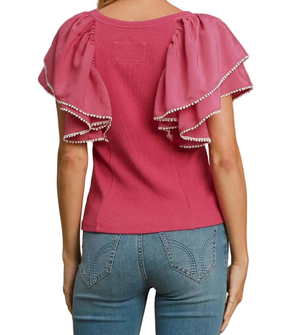 Pink blouse with ruffled sleeves and blue jeans on a beige background