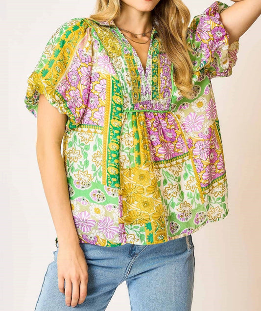 Woman wearing a colorful patterned blouse with a plain background