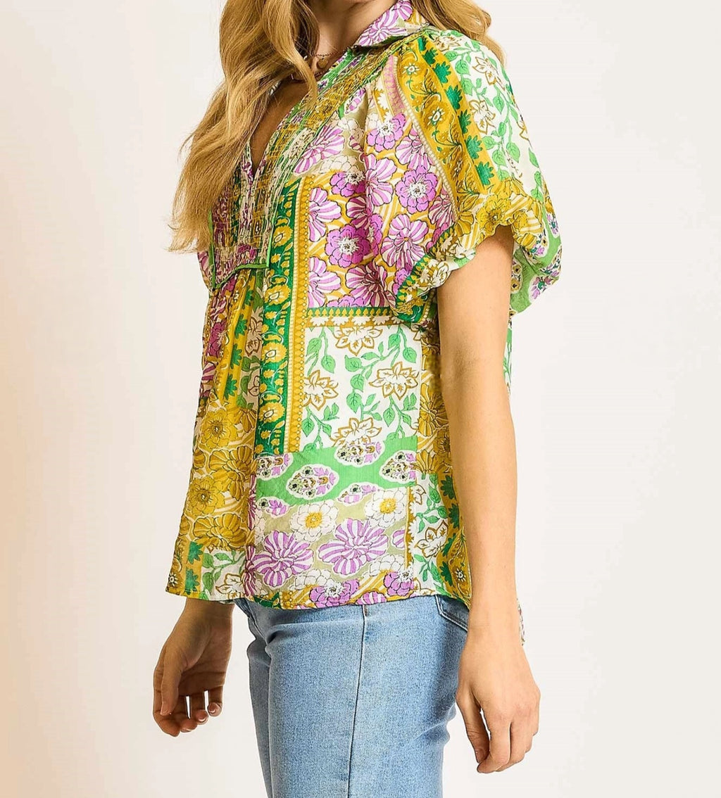 Woman wearing a colorful patterned blouse with a plain background