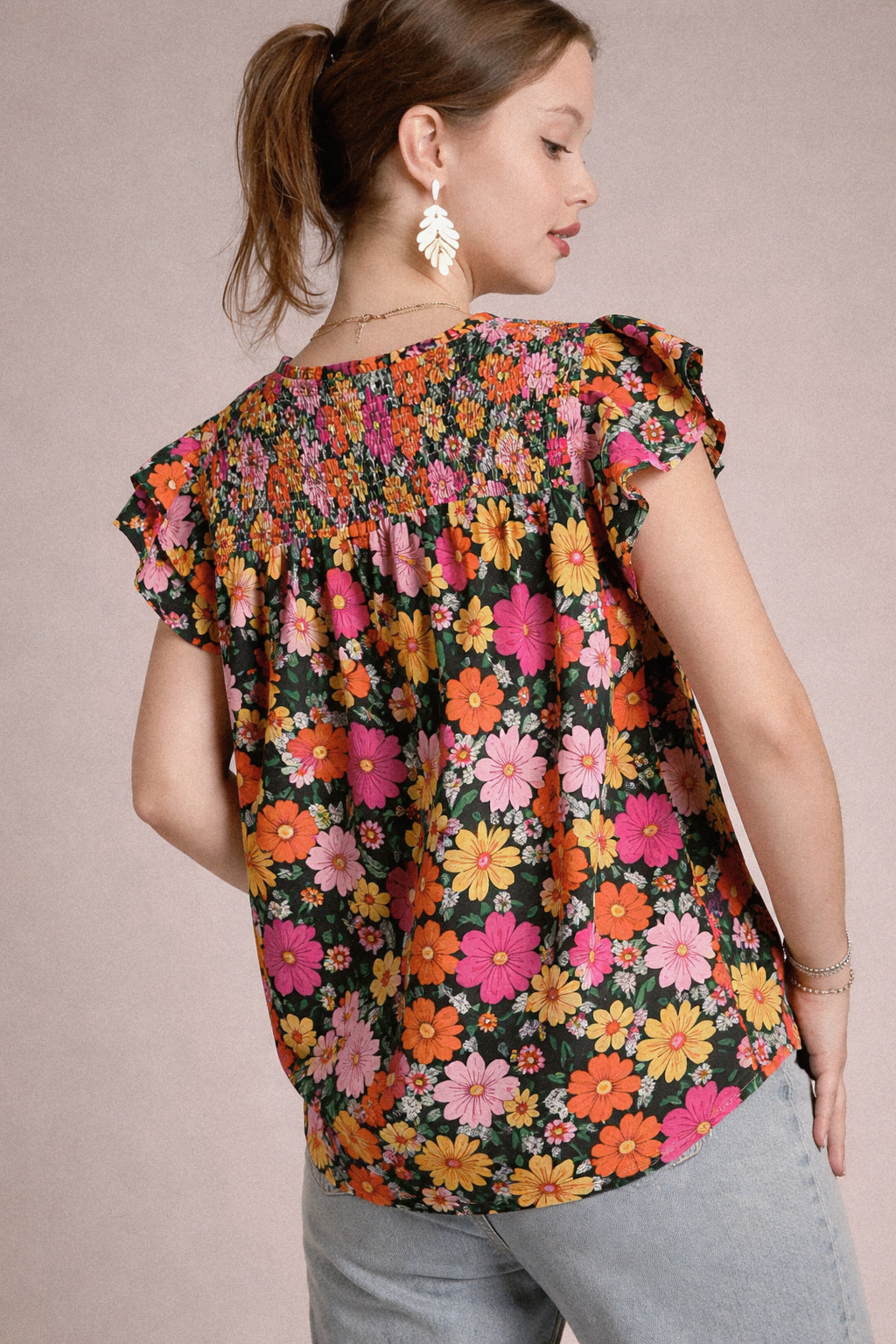 Woman wearing a colorful floral blouse against a neutral background