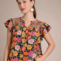 Woman wearing a colorful floral woman's top against a beige background
