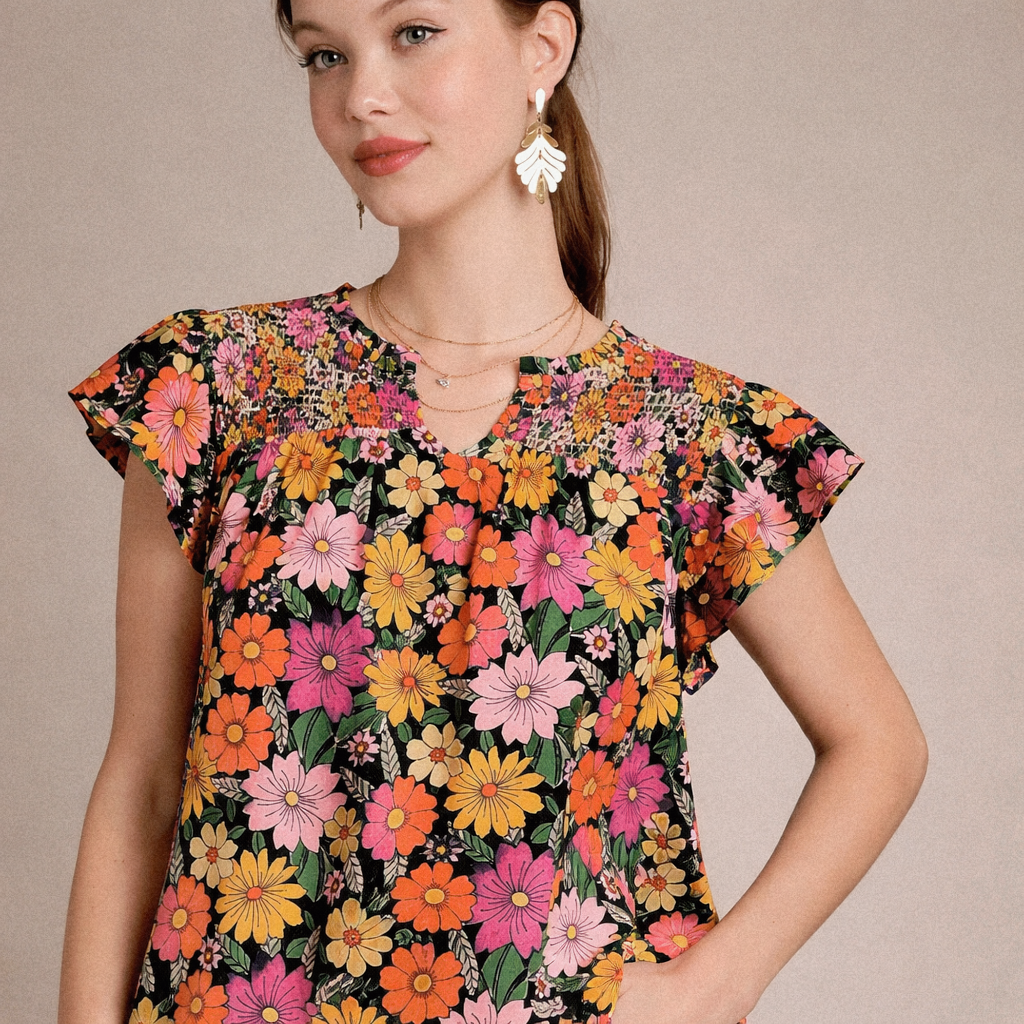 Woman wearing a colorful floral woman's top against a beige background